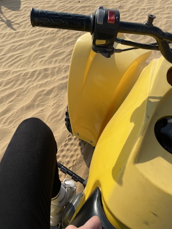 Close-up of a rider’s hands gripping the quad handlebars with desert landscape blurred behind.
