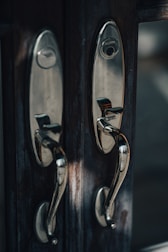 Polished chrome handles and hinges arranged neatly on a wooden surface.