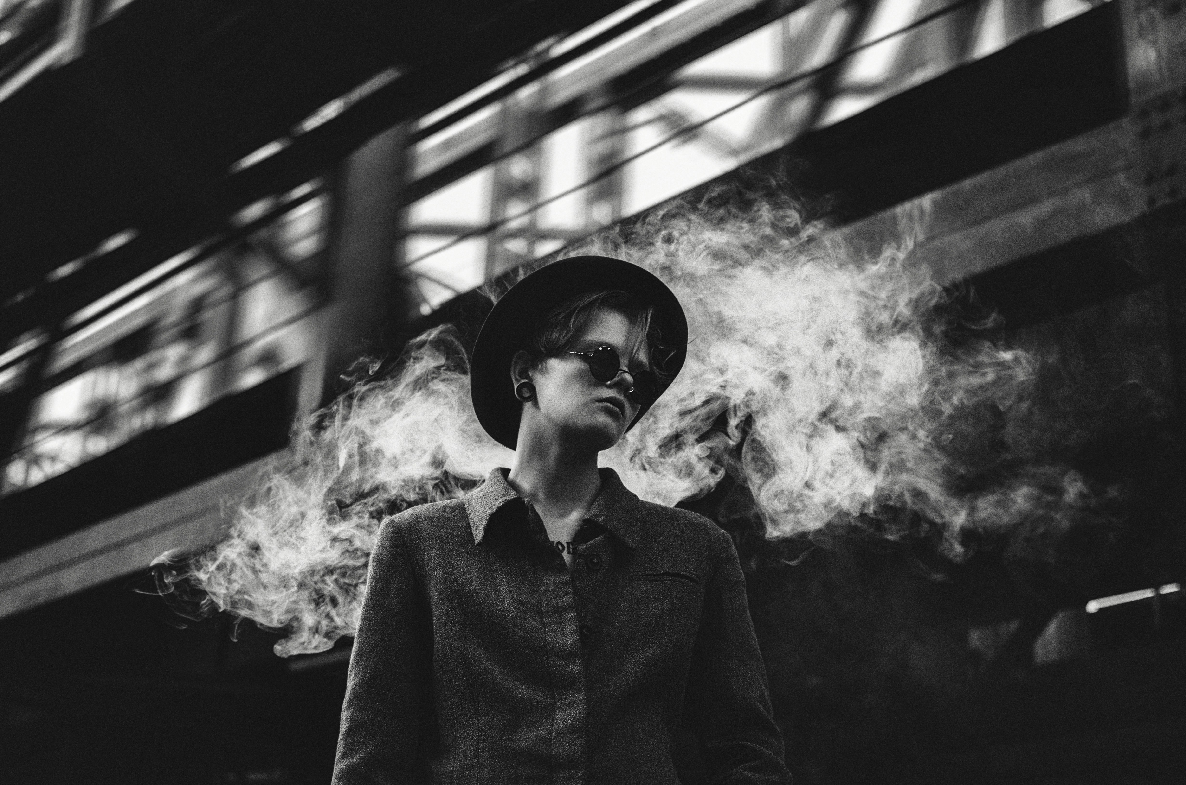 a man wearing a hat and glasses standing in front of a building