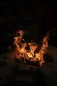 Close-up of a custom concrete fire pit glowing warmly at dusk.
