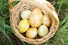 A basket overflowing with brightly painted Easter eggs resting on fresh, deep green grass.
