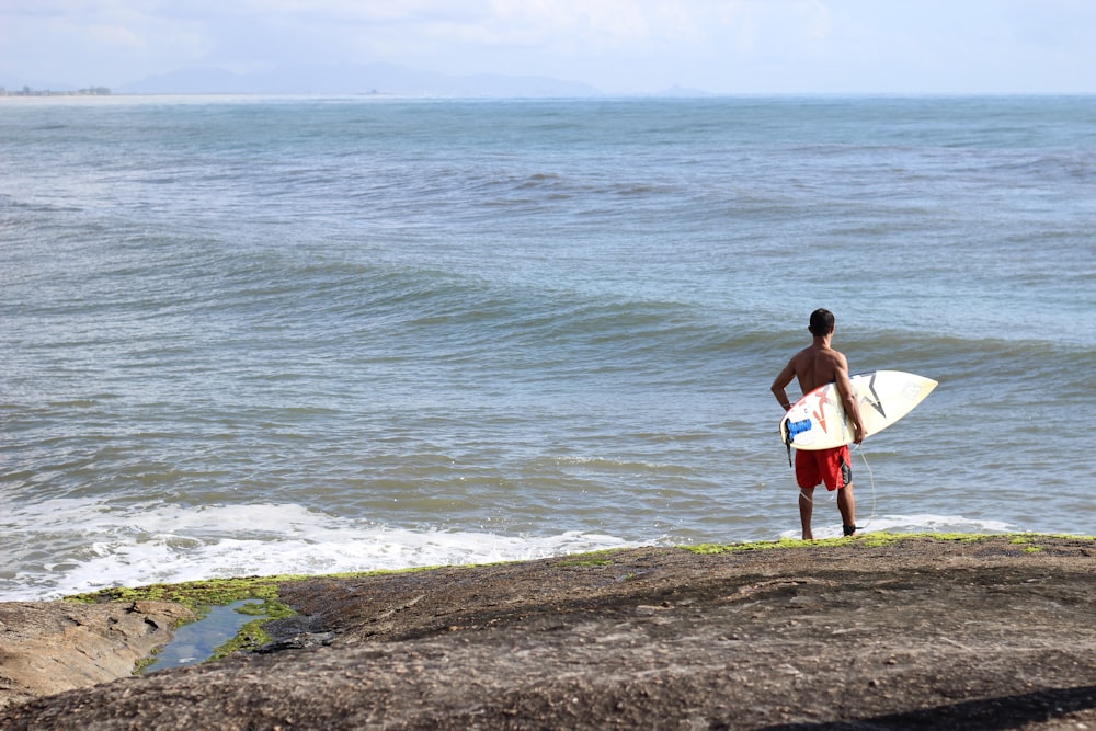 a man holding a surfboard on top of a beach