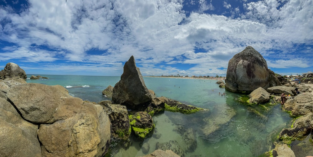 a body of water surrounded by rocks under a cloudy sky