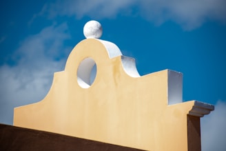 a yellow building with a white roof and a blue sky in the background