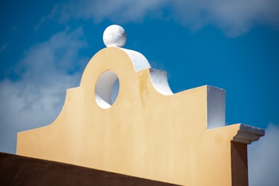 a yellow building with a white roof and a blue sky in the background