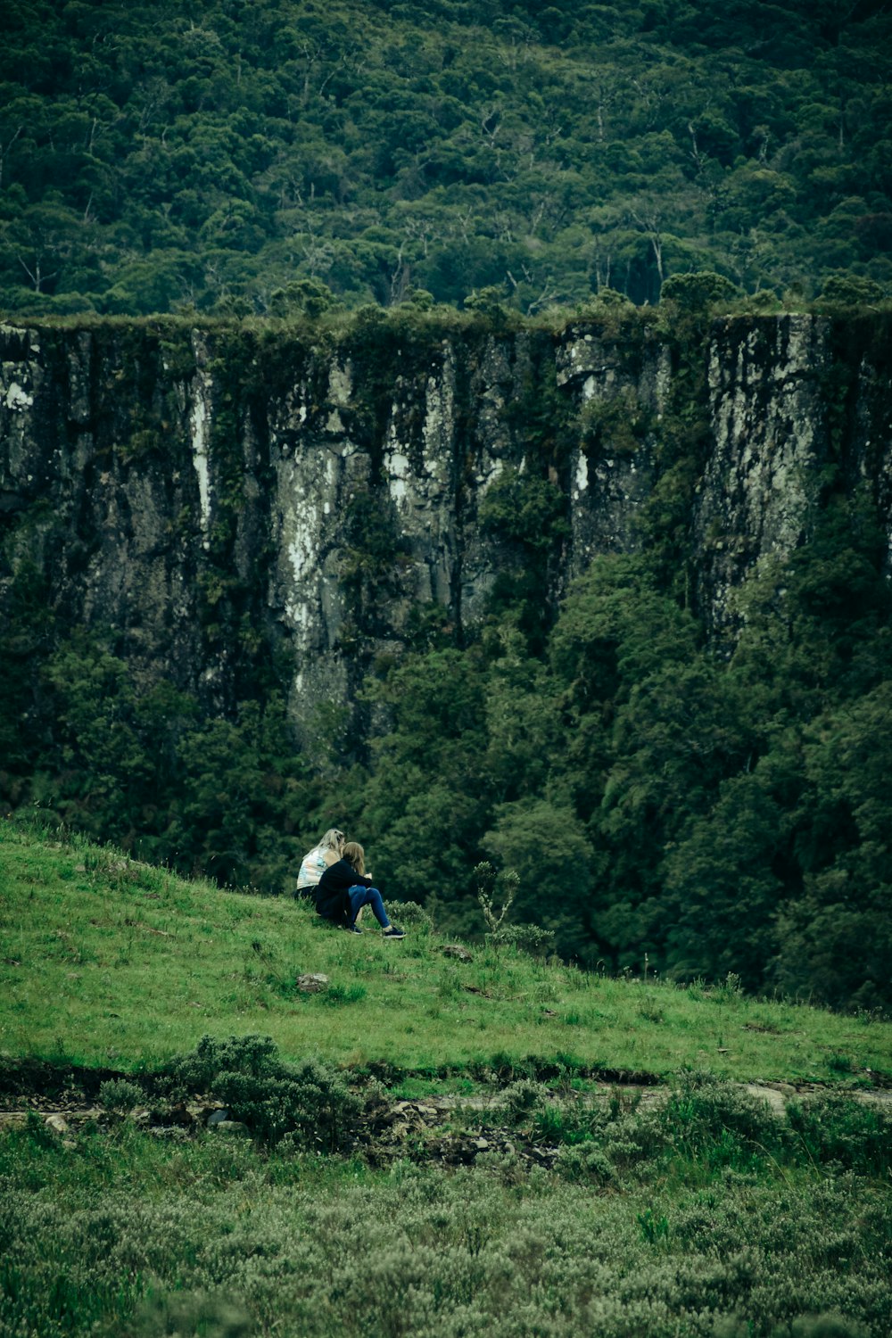 a person sitting on a hill with an umbrella