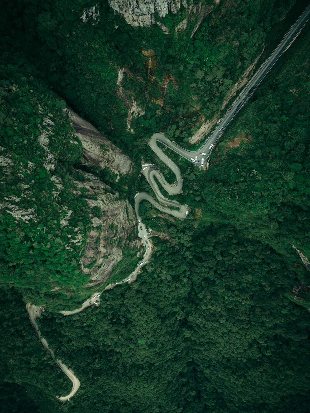 an aerial view of a winding road in the middle of a forest