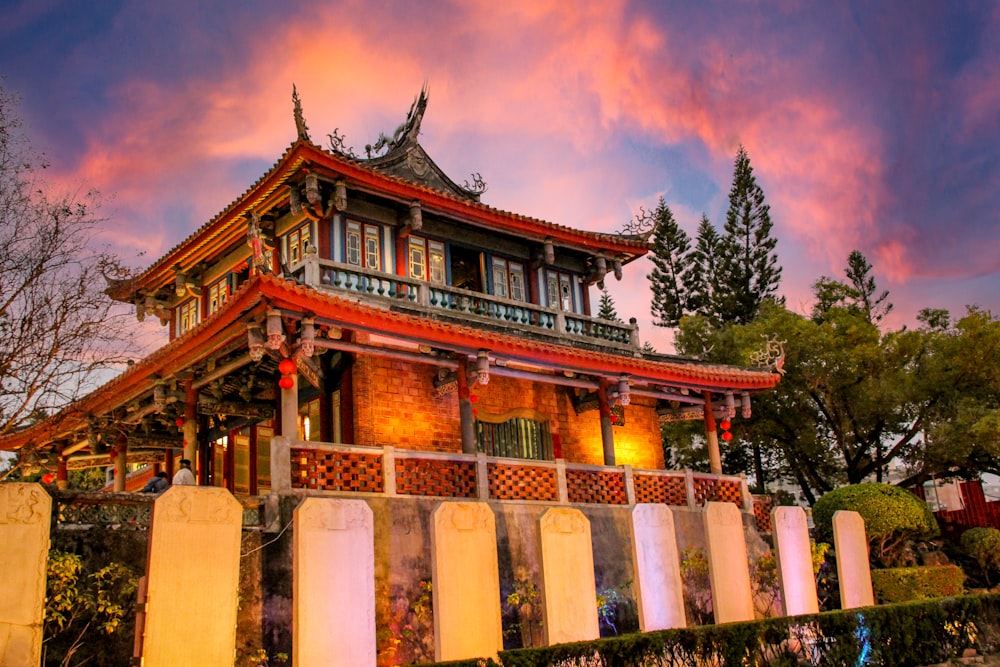 a tall building with a red roof sitting next to a lush green park