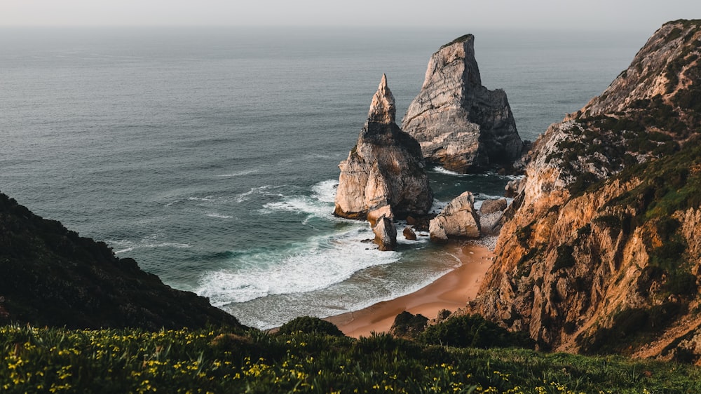 une grande formation rocheuse assise au sommet d’une plage au bord de l’océan