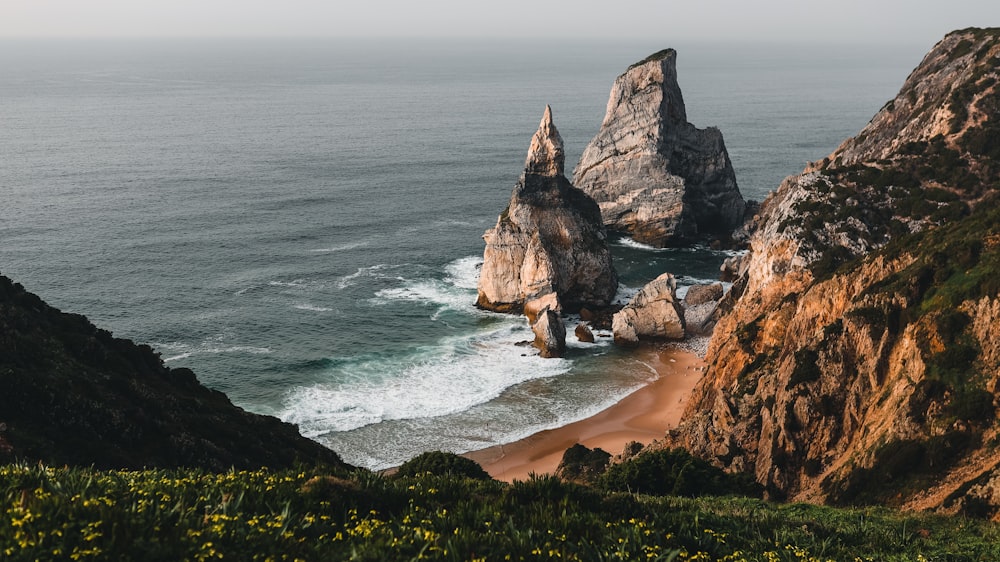 a large rock formation sitting on top of a beach next to the ocean