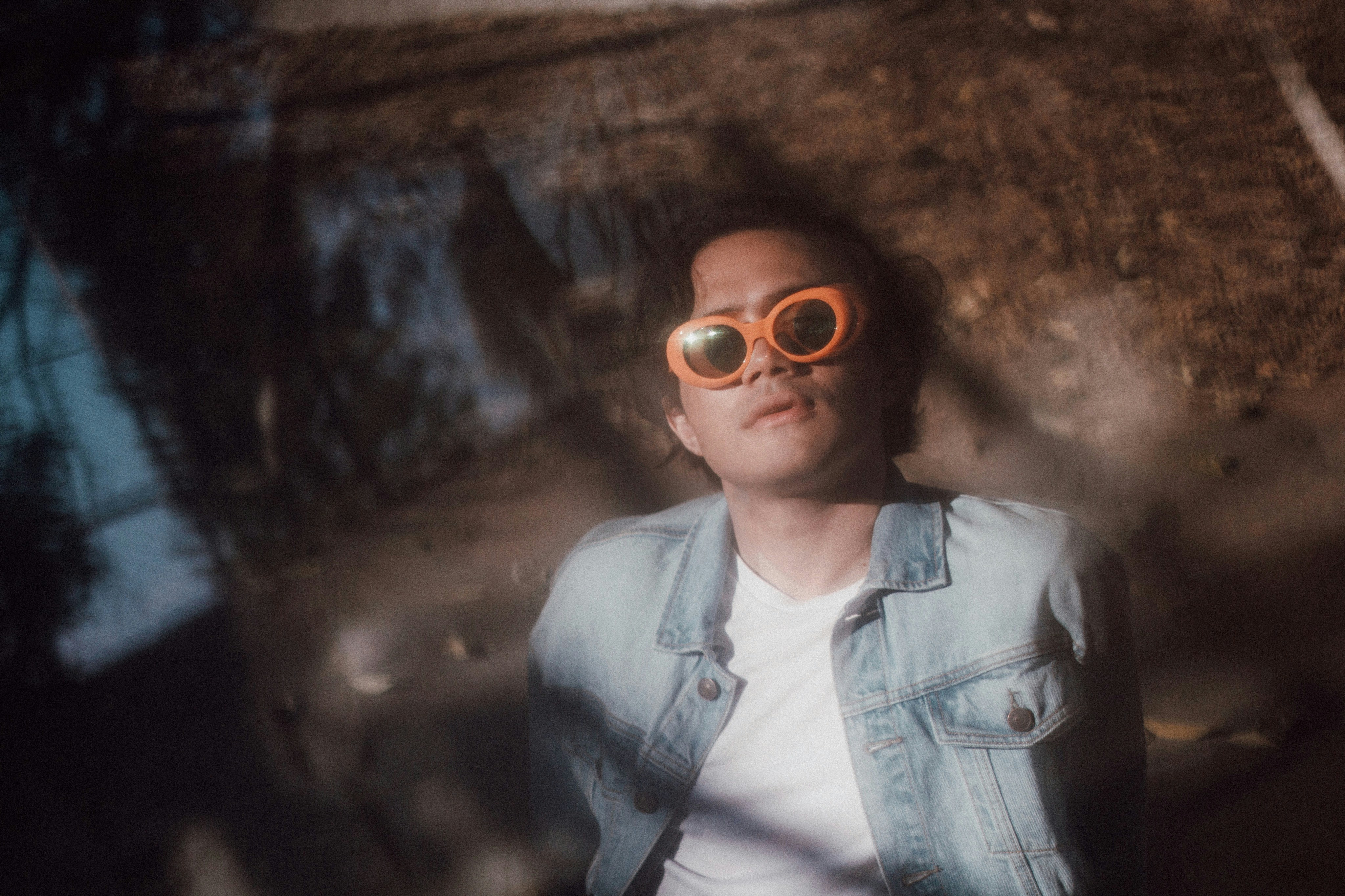 a woman wearing a denim jacket and orange sunglasses