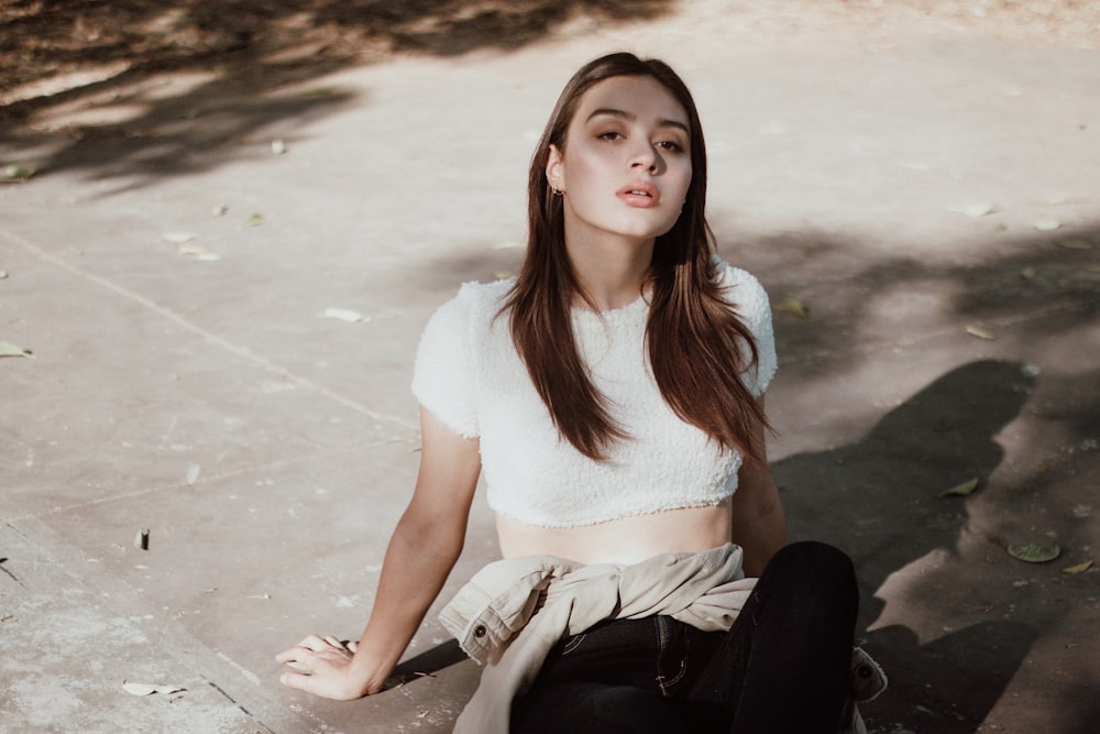 a woman sitting on the ground in a white top