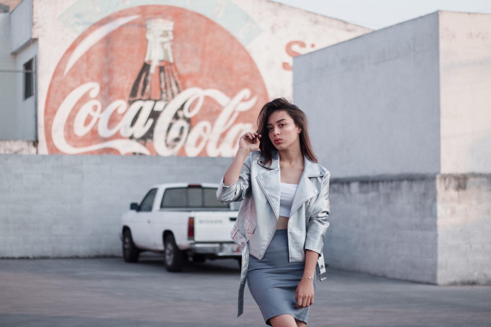 a woman walking down a street next to a coca cola sign