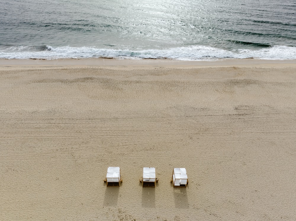 a couple of chairs sitting on top of a sandy beach