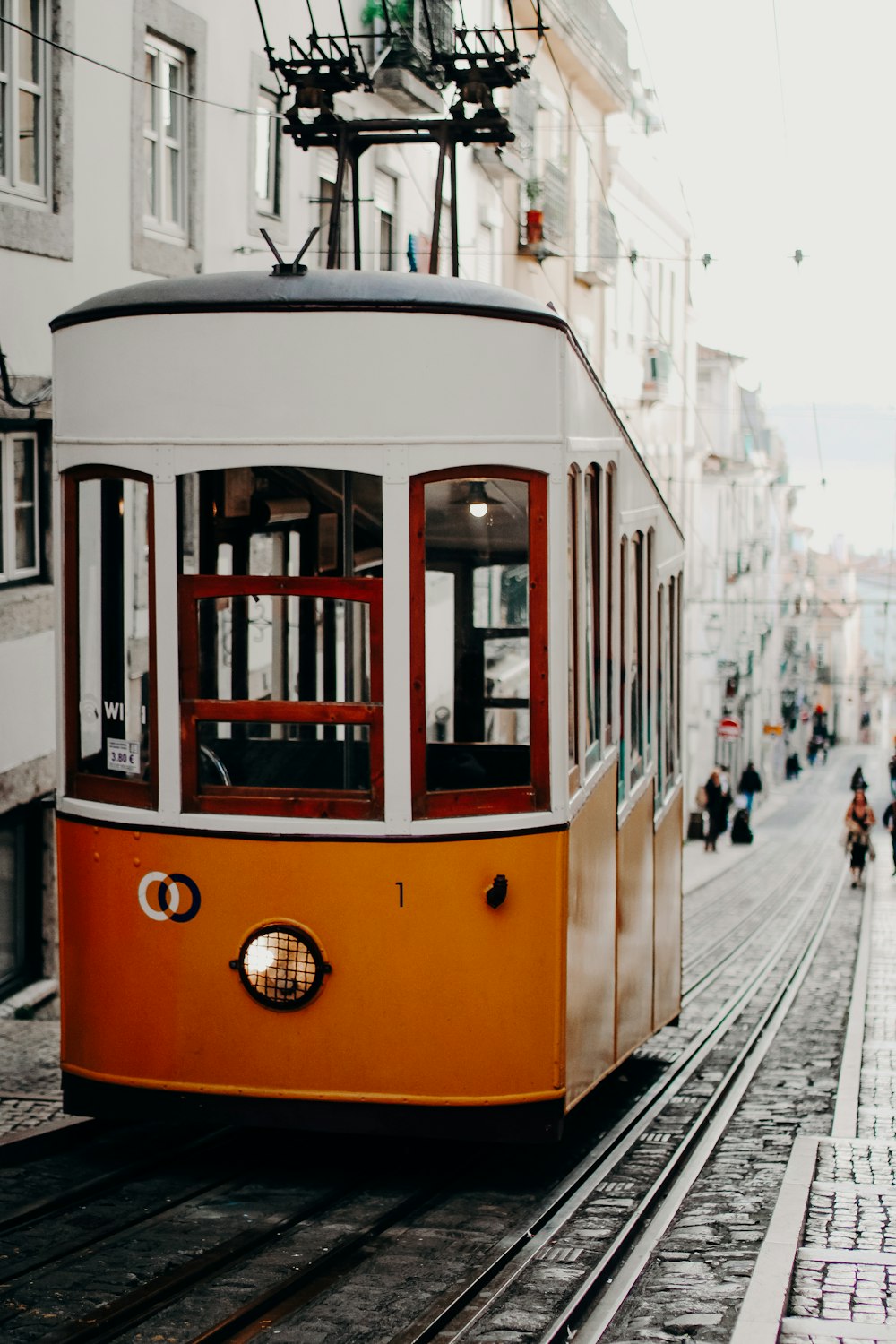 an orange and white trolley car traveling down a street