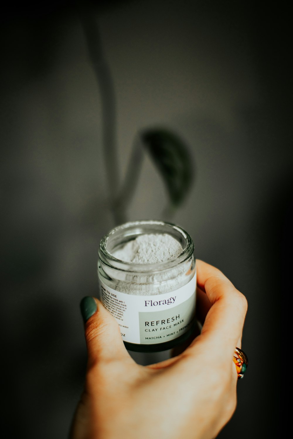 a hand holding a jar of white powder