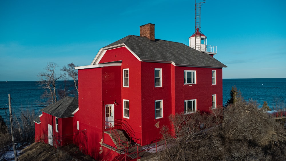 a red house sitting on top of a hill next to the ocean