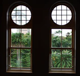 Master bedroom with floor-to-ceiling windows overlooking lush gardens.