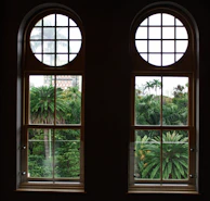 A luxurious suite with floor-to-ceiling windows overlooking a vibrant tropical landscape.