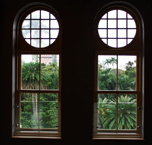 A bright living room with large, spotless windows offering a clear view of palm trees.