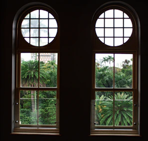 Master bedroom with floor-to-ceiling windows overlooking lush gardens.