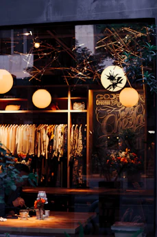 A cozy boutique corner showcasing modern women's clothing on wooden hangers with soft natural lighting.