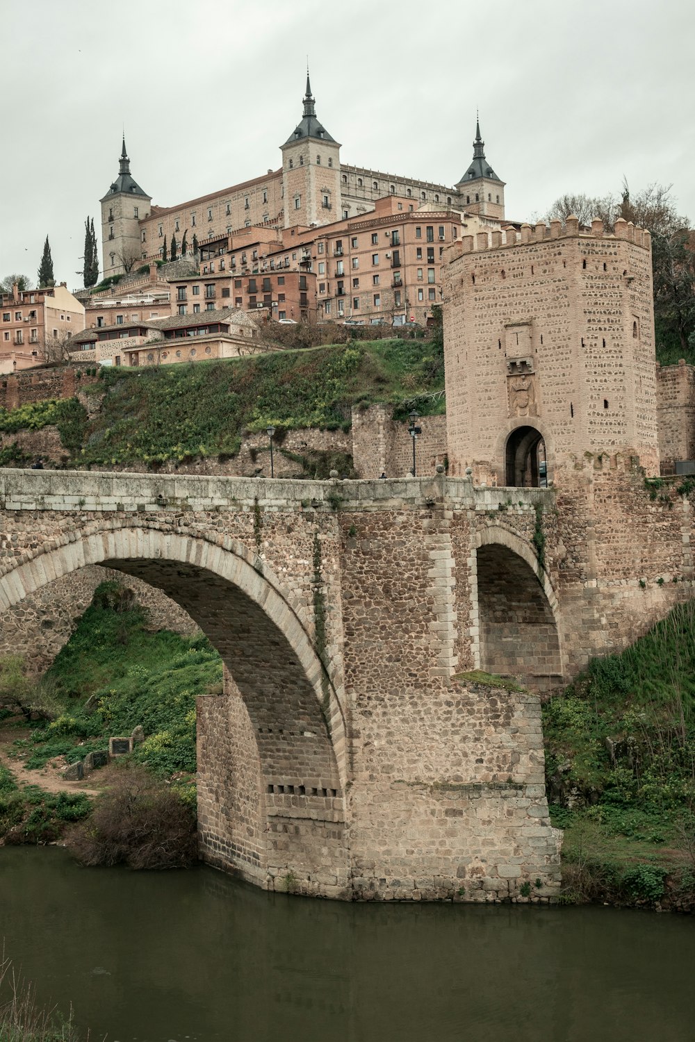 a stone bridge over a river with a castle in the background