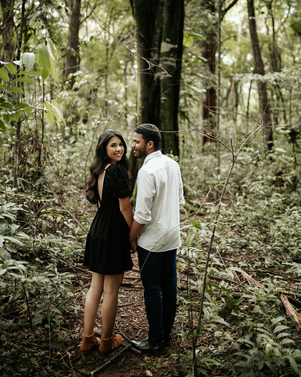 a man and a woman standing in the woods