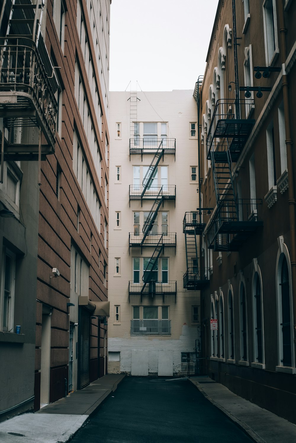 a narrow city street with buildings and fire escapes