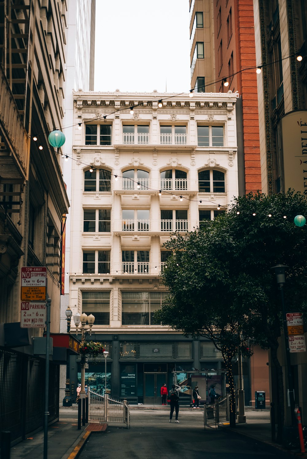 a couple of people walking down a street next to tall buildings