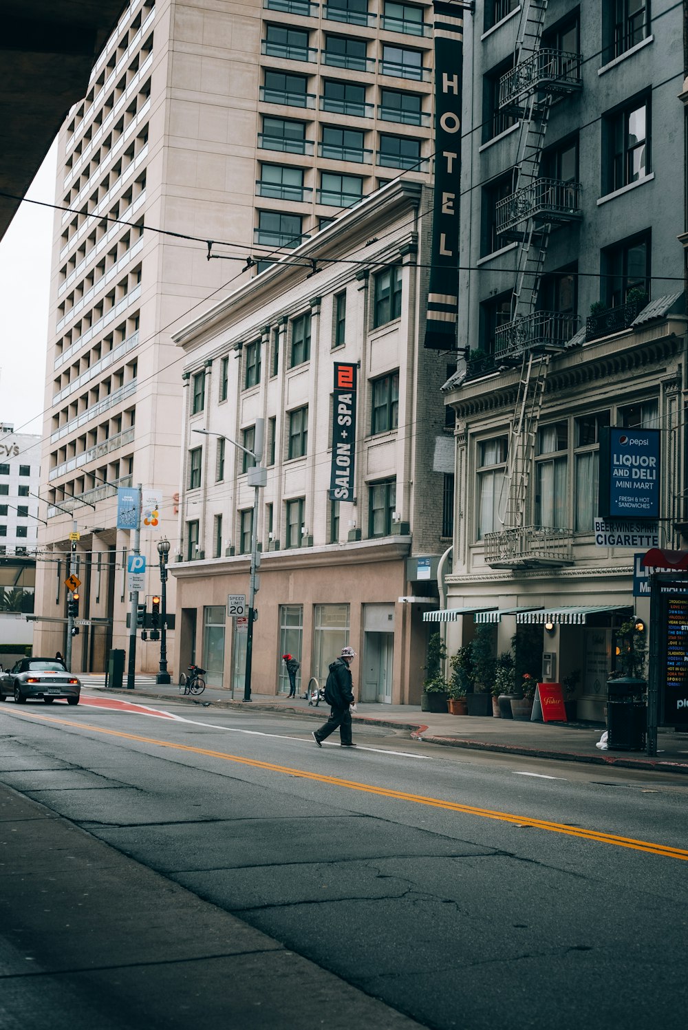 a man walking down a street next to tall buildings