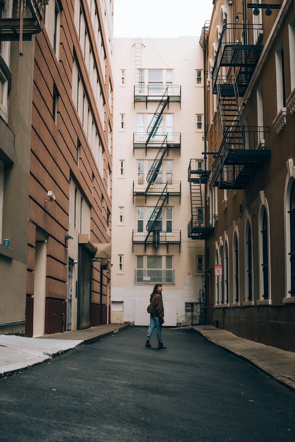 a man walking down a street next to tall buildings