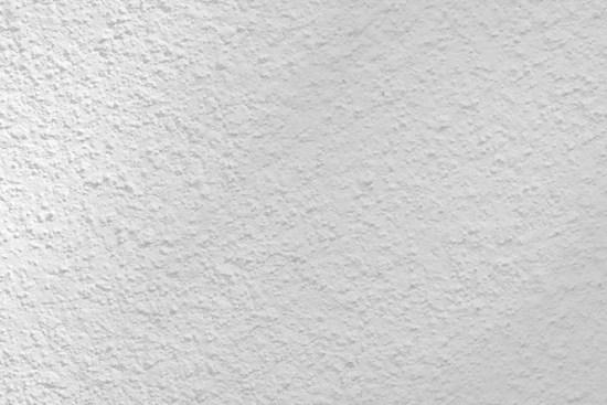 A close-up view of a textured white surface, possibly a plastered or stucco wall. The surface has a rough, uneven finish with small variations and grooves, creating a subtle pattern.
