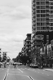 A monochrome photograph of a bustling city street with people crossing under soft morning light.