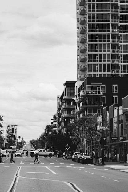 A striking black-and-white photo of a busy urban street with people crossing and tall buildings in the background.