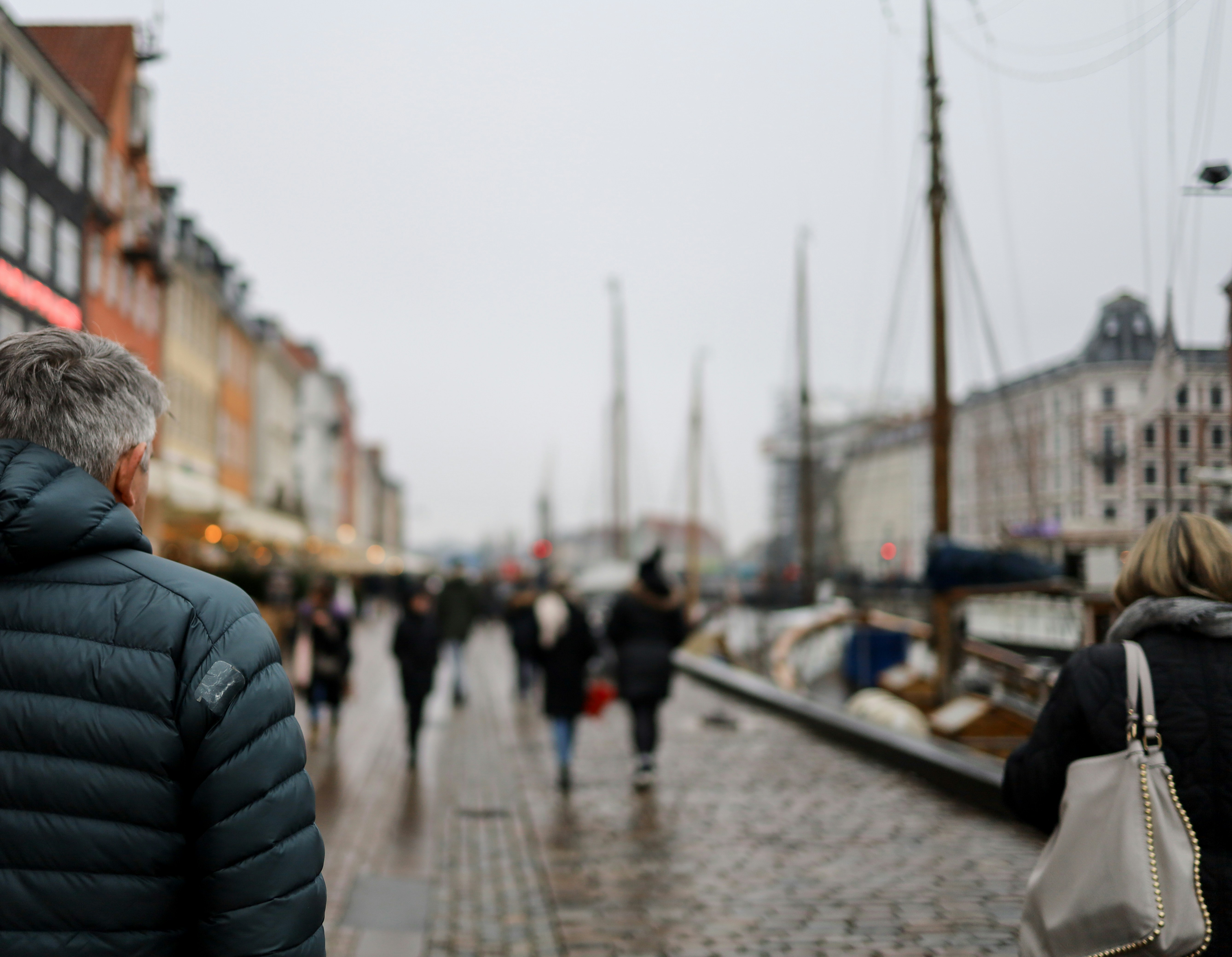 a group of people walking down a wet sidewalk