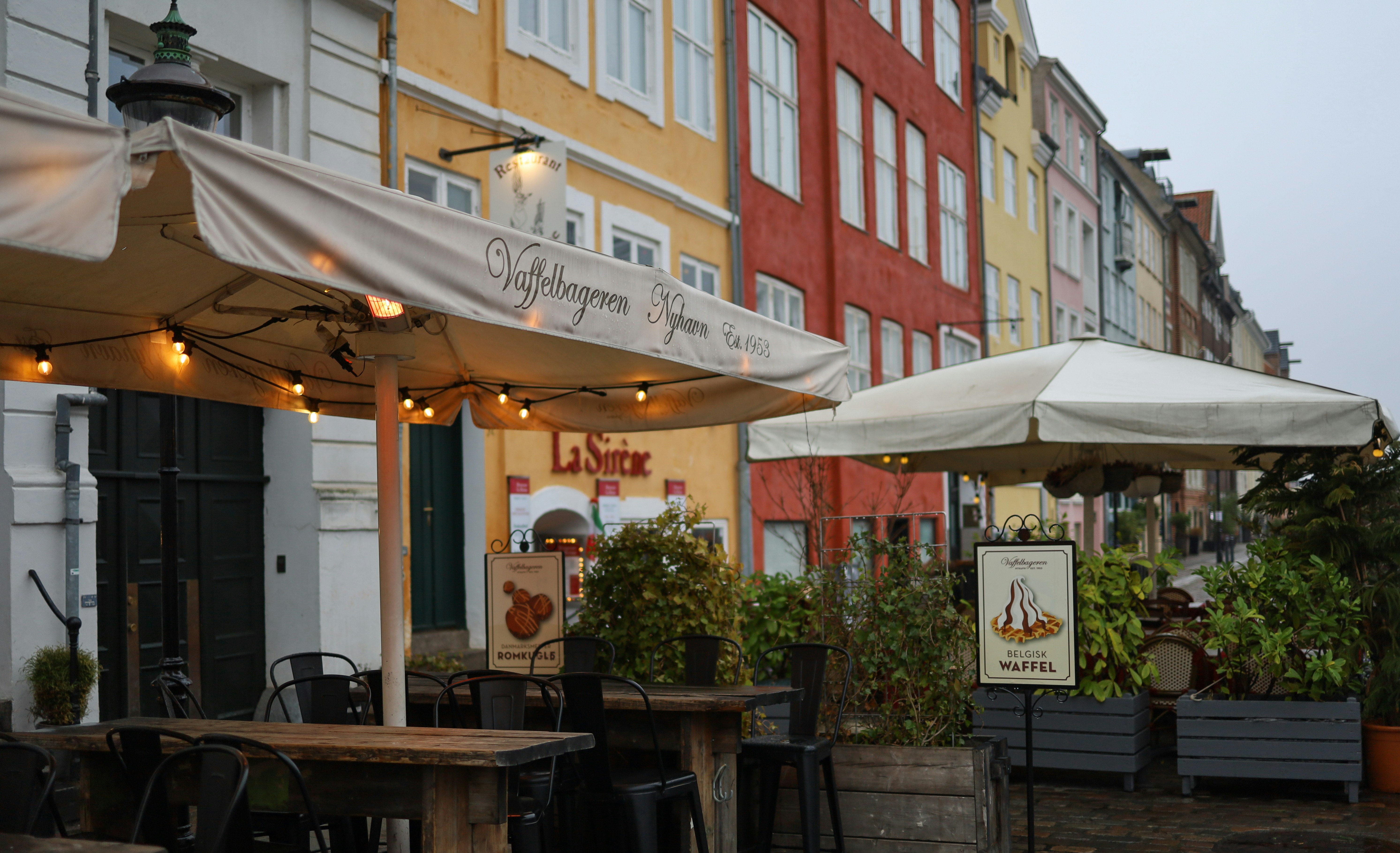 an outdoor cafe with tables and umbrellas on a rainy day