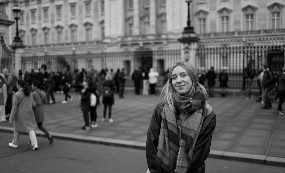 a black and white photo of a woman standing in front of a building