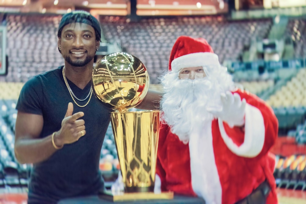 a man standing next to a golden trophy next to a santa clause