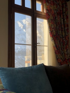 A comfortable room with traditional Kashmiri decor and a window framing the mountain landscape