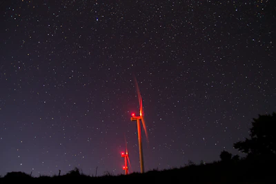 A sleek wind turbine with glowing cyan accents under a dark sky, symbolizing AI-driven optimization.