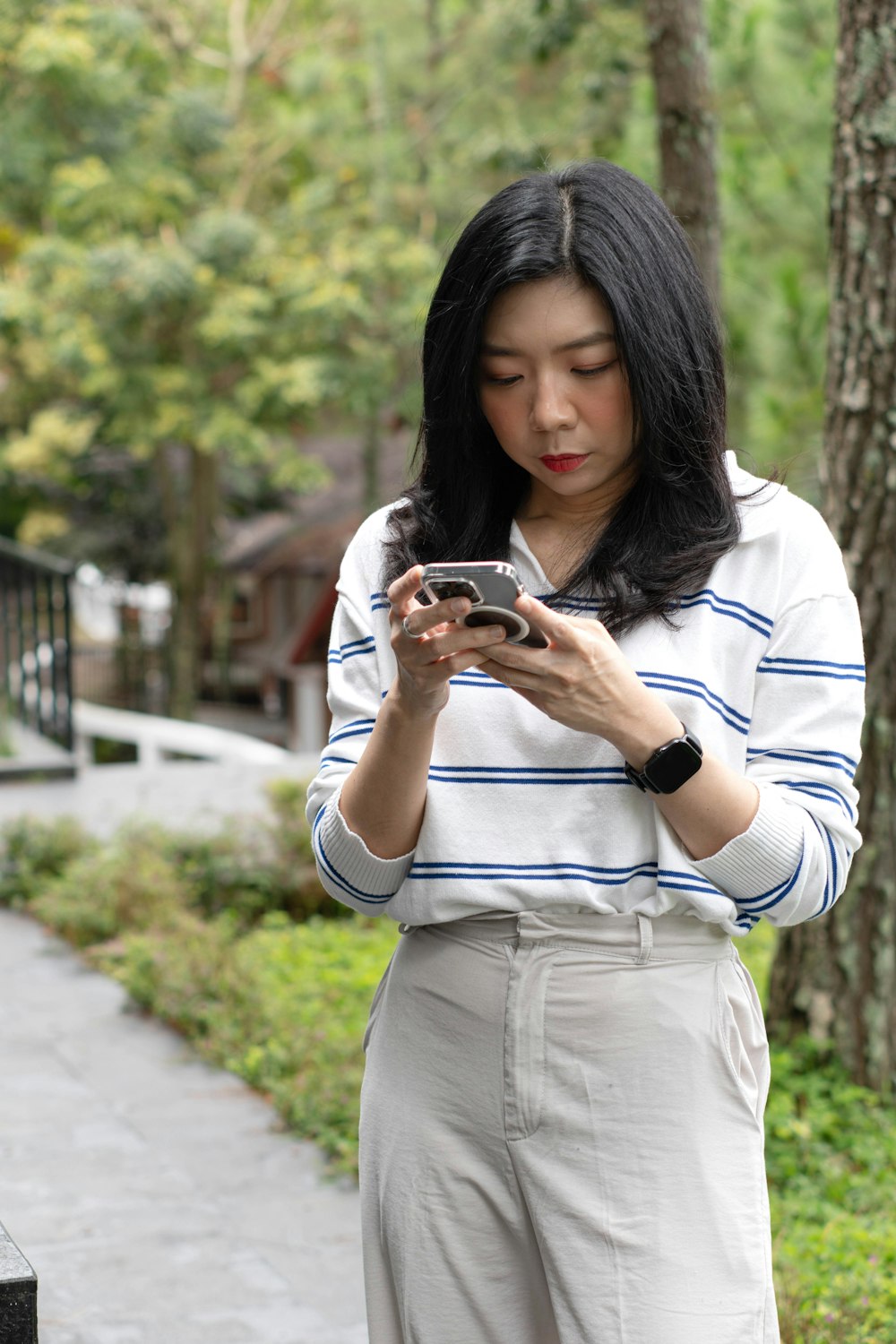 a woman standing on a sidewalk looking at her cell phone