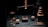 An arrangement of vintage weighing scales is prominently displayed, surrounded by copper weights and a stack of circular, graduated weights on the right. The background contrasts with the dark tones, highlighting the copper's sheen.