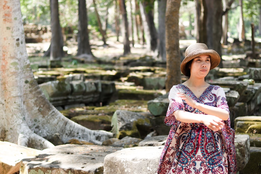 a woman wearing a hat standing in a forest