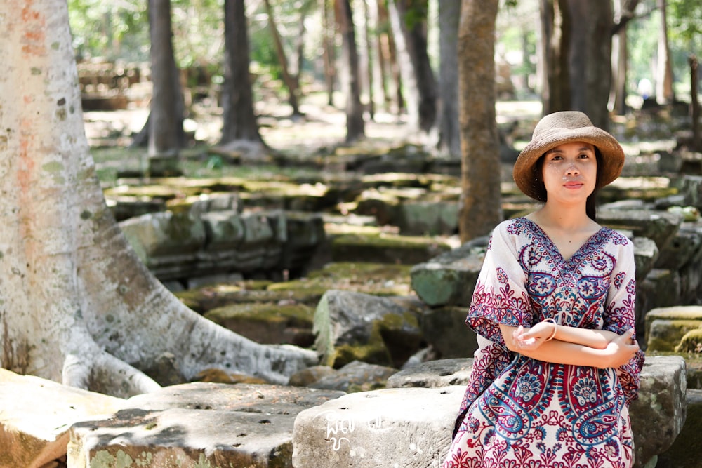 a woman wearing a hat standing in a forest