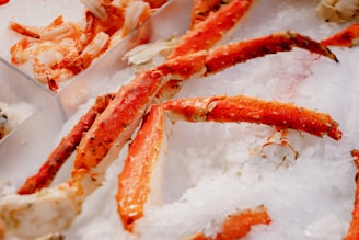 Large crab legs are placed on a bed of crushed ice with some shrimp visible in the background, creating a fresh seafood display.