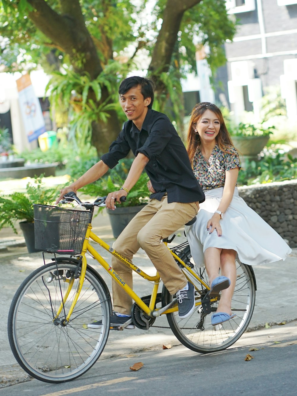 a man and a woman riding a bike down a street