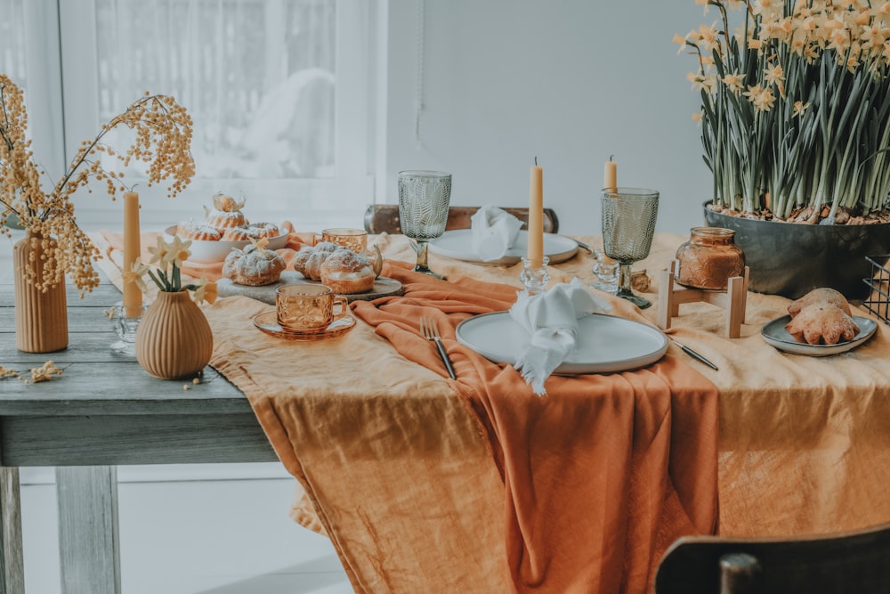 a table set with plates, cups, and vases