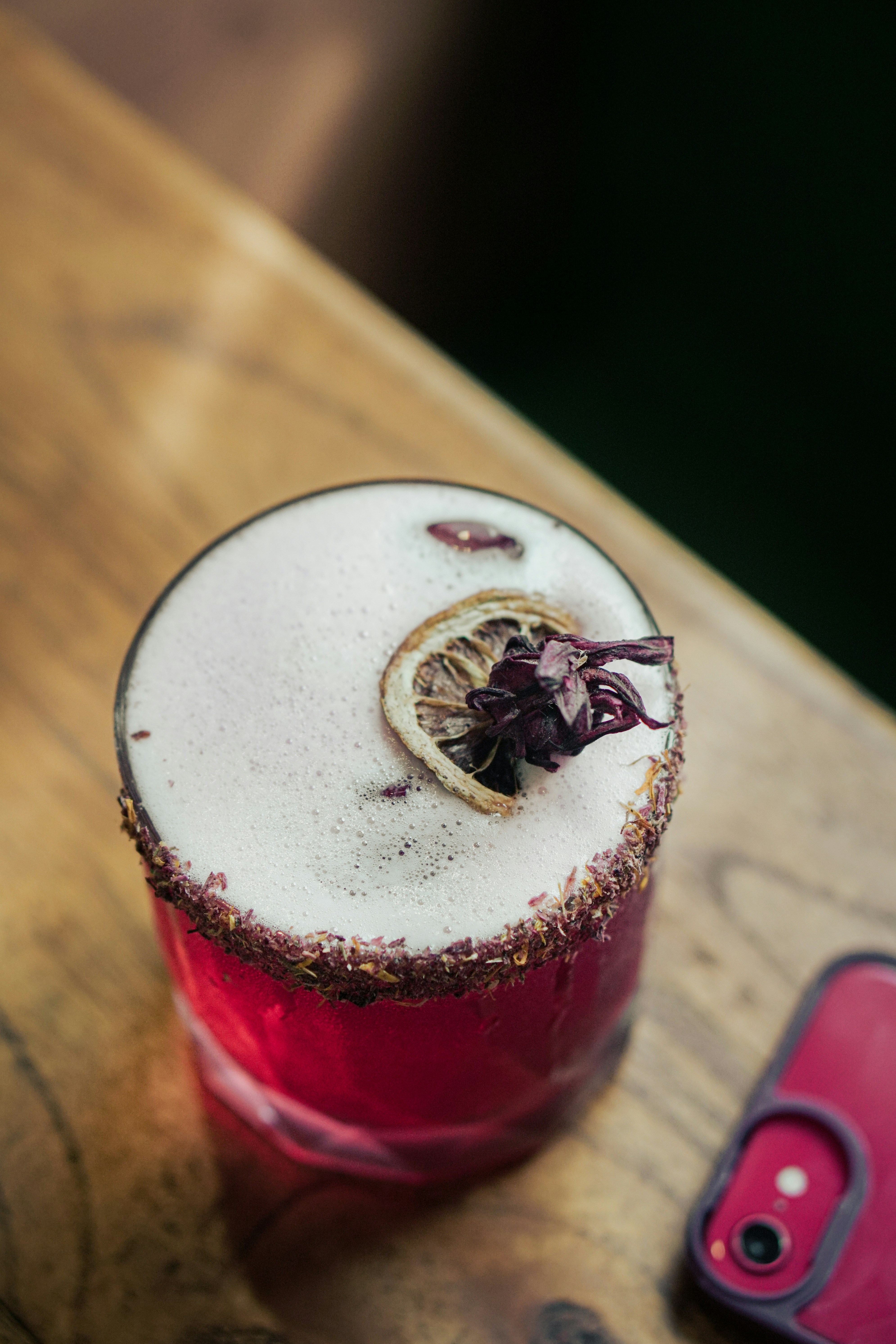 a drink sitting on top of a wooden table next to a cell phone