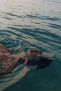 a man swimming in the ocean with his head above the water